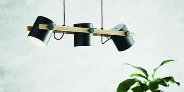 Three matte black cylindrical pendants suspended from a horizontal timber beam against a light grey wall