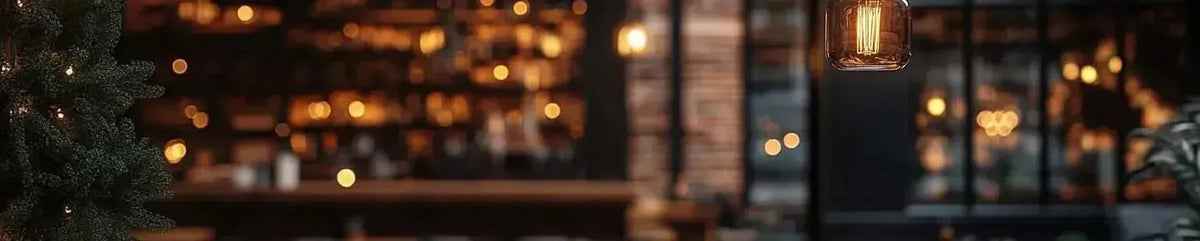 Warm amber filament pendant light hanging in a moody bar interior with exposed brick and soft bokeh fairy lights