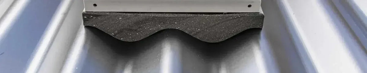 White Corromount base with a dark grey textured foam seal mounted on a corrugated metal roof sheet