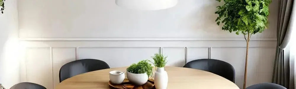 White fabric drum pendant light suspended over a round timber dining table in a contemporary room with wall panelling