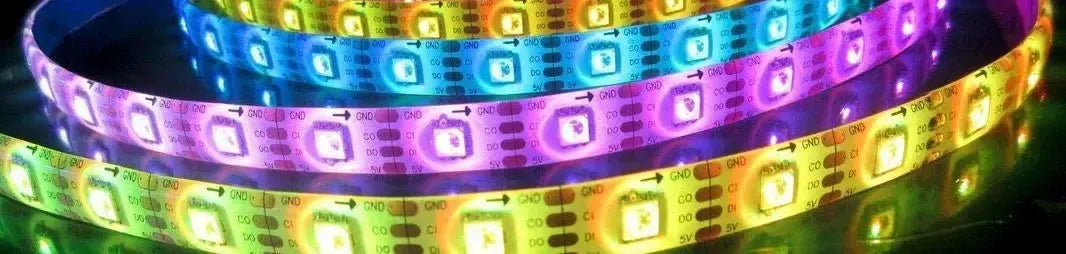 Flexible LED strip light with multi-coloured glowing diodes coiled on a dark reflective surface