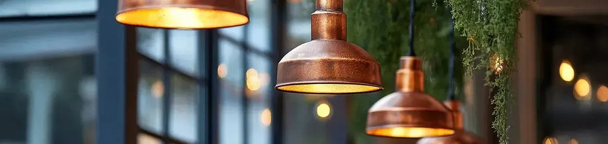 Rustic copper pendant lights with a weathered finish hanging in a lush indoor garden setting