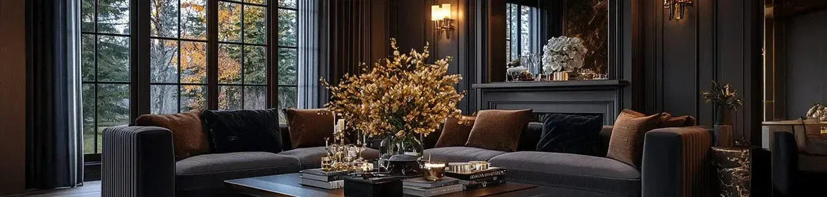 Wall mounted brass sconces with warm glowing lights in a dark moody living room with plush grey sofas