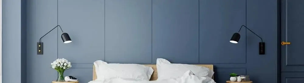 Matte black adjustable wall lights mounted on a blue panelled bedroom wall above a timber bed frame