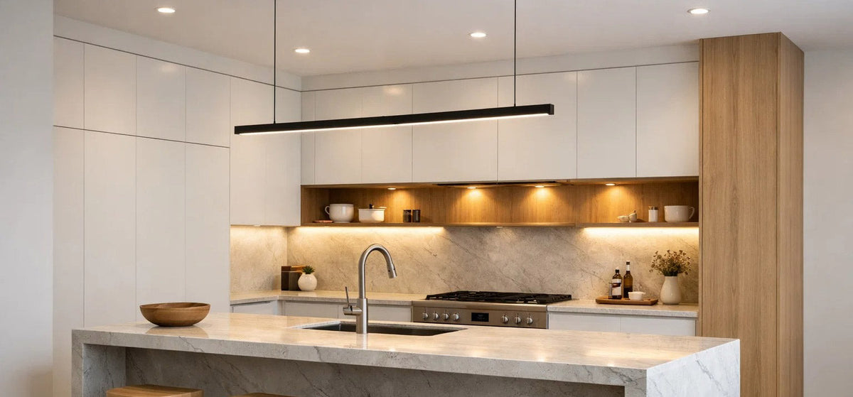 Slim black linear pendant light suspended above a marble kitchen island in a modern white and timber kitchen