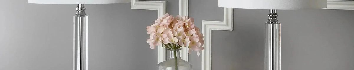 Crystal table lamps with cylindrical glass bases and white fabric shades against a grey wall with white moulding
