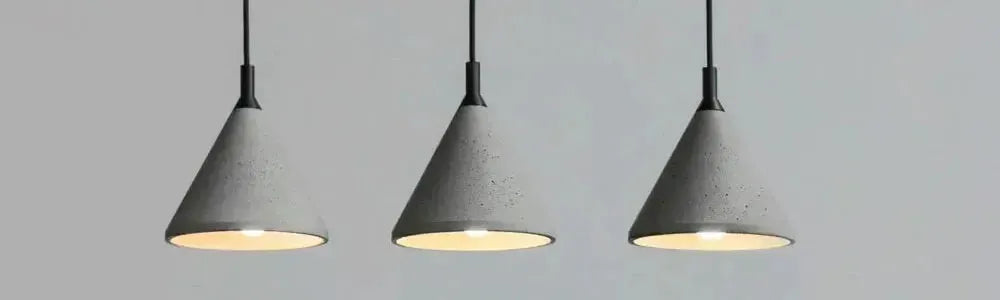 Three grey conical concrete pendant lights with black suspension cables against a plain light grey background