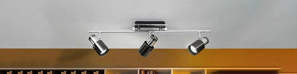 Three cylindrical black and chrome spotlights mounted on a horizontal bar attached to a white ceiling