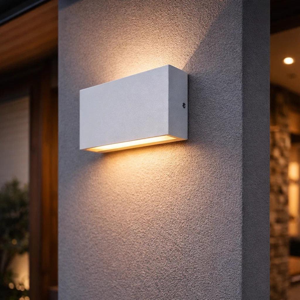 Modern white rectangular LED up and down wall light mounted on an exterior textured wall.